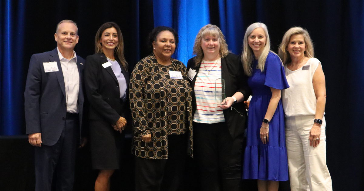 Liz Eagan holding award and posing with Region 13 representatives